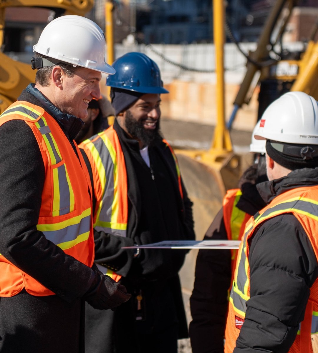 Evan Solomon speaking with construction workers at a housing development site